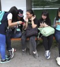 South Korean middle school students use their smartphones at a bus station in Seoul, South Korea, Friday, May 15, 2015. (AP Photo/Ahn Young-joon)