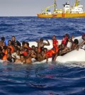 In this photo taken on Sunday, April 17, 2016 migrants ask for help from a dinghy boat as they are approached by the SOS Mediterranee's ship Aquarius, background, off the coast of the Italian island of Lampedusa. The European Union's border agency says the number of migrants crossing the Mediterranean Sea to Italy more than doubled last month. Frontex said in a statement on Monday that almost 9,600 migrants attempted the crossing, one of the most perilous sea voyages for people seeking sanctuary or jobs in Europe.