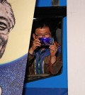 A supporter takes pictures between pictures of the South Korean President-elect Moon Jae-In, as Moon speaks to his supporters after he was declared the winner of the election South Korea, May 10, 2017. Credit Jeon Heon-Kyun/European Pressphoto Agency