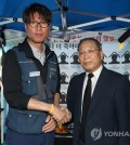 SsangYong Motor Co. CEO Choi Jong-sik (R) shakes hands with Kim Deuk-joong, the manager of the Korean Metal Workers' Union's SsangYong Motor branch, at a temporary memorial altar for late SsangYong Motor workers in Seoul on Sept. 13, 2018. (Yonhap)