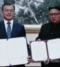 The captured image of a live broadcast from Pyongyang shows South Korean President Moon Jae-in (L) and North Korean leader Kim Jong-un holding their joint declaration signed at the end of their bilateral summit held in the North Korean capital on Sept. 19, 2018. (Yonhap)