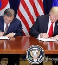 South Korean President Moon Jae-in (L) and U.S. President Donald Trump sign the official document on the revised free trade agreement between the two allies at Lotte New York Palace in New York on Sept. 24, 2018. (Yonhap)