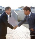 President Moon Jae-in (L) shakes hands with the head of Gangjeong, a small fishing town on the southern coast of Jeju Island, as he meets with local residents on Oct. 11, 2018. (Yonhap)