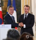 South Korean President Moon Jae-in (L) and French President Emmanuel Macron clasp hands after holding a joint press conference to announce the outcome of their bilateral summit at the Elysee Palace in Paris on Oct. 15, 2018. (Yonhap)