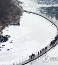 Hikers walk on a floating bridge across the frozen Hantan River in Cheolwon County, Gangwon Province, on Jan. 19, 2023. (Yonhap)