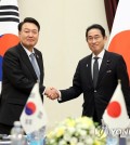 South Korean President Yoon Suk Yeol (L) and Japanese Prime Minister Fumio Kishida shake hands during their meeting on the sidelines of a summit of the North Atlantic Treaty Organization in Vilnius, Lithuania, on July 12, 2023. (Yonhap)