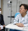 Lee Jae-myung, chair of the Democratic Party, is briefed by a party official on Sept. 28, 2023, at a hospital in Seoul where he is under treatment following a 24-day hunger strike. (Yonhap)