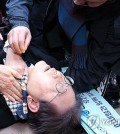 Lee Jae-myung, leader of the main opposition Democratic Party, lies down after he was attacked by an assailant on the left side of his neck during a visit to the construction site of an airport on Gadeok Island off the southeastern port city of Busan on Jan. 2, 2024. (Yonhap)