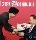 Rep. Lee Sang-min (R) receives a bouquet of flowers from the ruling People Power Party's (PPP) chairman, Han Dong-hoon, at the PPP's emergency committee meeting held in Seoul on Jan. 8, 2024. (Yonhap)