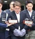 Popera star Kim Ho-joong is escorted by police officers from the Seoul Central District Court to wait in custody at the Gangnam Police Station on May 24, 2024, following a court hearing on an arrest warrant. (Yonhap)