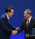 President Yoon Suk Yeol (L) shakes hands with Chinese Premier Li Qiang after holding a joint press conference with Japanese Prime Minister Fumio Kishida following their trilateral summit in Seoul on May 27, 2024, in this photo provided by Yoon's office. (PHOTO NOT FOR SALE) (Yonhap)
