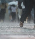 People walk near Gwanghwamun Square in Seoul on July 17, 2024, when a heavy rain alert was issued across the greater Seoul region for the first time this year. (Yonhap)