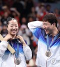 South Korea extended its medal-winning streak to four days at the Paris Olympics on Tuesday, picking up a bronze medal each in table tennis and judo. Shin Yu-bin (L) and Lim Jong-hoon of South Korea celebrate after winning the bronze medal in the mixed doubles table tennis event at the Paris Olympics at South Paris Arena 4 in Paris on July 30, 2024. (Yonhap) Shin Yu-bin (L) and Lim Jong-hoon of South Korea celebrate after winning the bronze medal in the mixed doubles table tennis event at the Paris Olympics at South Paris Arena 4 in Paris on July 30, 2024. (Yonhap) The first medal of the day was a drought buster, as Lim Jong-hoon and Shin Yu-bin captured the bronze medal in the mixed doubles table tennis event for South Korea's first ping pong medal in 12 years. They defeated Wong Chun Ting and Doo Hoi Kem of Hong Kong 4-0 (11-5, 11-7, 11-7, 14-12) in the third-place contest. The South Koreans took the first three games with relative ease, but Chun and Doo pushed back and held a 10-8 lead in the fourth game, a point away from extending the match. But South Korea won the next two points for the deuce, and closed out the Hong Kong team at 14-12 on a long return by Wong. The North Korean team of Ri Jong-sik and Kim Kum-yong won silver in the mixed doubles for their country's first medal in Paris. South Korea also earned a bronze medal in judo, with Lee Joon-hwan defeated world No. 1 from Belgium, Matthias Casse, in one of two bronze medal contests. Lee grabbed his decisive "waza-ari," or a half point, 48 seconds into the sudden-death extra period to win bronze in his Olympic debut. South Korea has so far won five golds, three silvers and three bronzes to rank fifth in the medal table. Lee Joon-hwan of South Korea holds up his bronze medal won in the men's -81-kilogram judo event at the Paris Olympics at Champ-de-Mars Arena in Paris on July 30, 2024. (Yonhap) Lee Joon-hwan of South Korea holds up his bronze medal won in the men's -81-kilogram judo event at the Paris Olympics at Champ-de-Mars Arena in Paris on July 30, 2024. (Yonhap) Elsewhere on Tuesday, South Korea settled for fourth place in the 10-meter air pistol mixed team event on Tuesday, after Lee Won-ho and Oh Ye-jin lost to Sarabjot Singh and Manu Bhaker of India 16-10 in the bronze medal contest. Oh, the women's 10m air pistol champion, missed out on her second medal of the Paris Games. This was Lee's second fourth-place finish after the men's 10m air pistol event. The men's 4x200-meter freestyle relay team finished sixth in South Korea's very first appearance in an Olympic swimming relay final. The team of Yang Jae-hoon, Lee Ho-joon, Kim Woo-min and Hwang Sun-woo finished the 800m competition in 7:07.26, nearly six full seconds worse than their national record. The women's epee fencing team lost to France 37-31 in the quarterfinals, as its bid for a second straight medal came crashing down in the first match. The team of Song Se-ra, Kang Young-mi, Lee Hye-in and Choi In-jeong won the silver medal together at the 2021 Tokyo Olympics. They were reunited for Paris after Choi came out of retirement earlier this year, but couldn't recapture their magic from three years ago. The women's handball team lost to Norway 26-20 in Group A. This was South Korea's second straight defeat, as its hopes of qualifying for the quarterfinals took another blow. Im Ae-ji reached the quarterfinals of the women's 54-kilogram boxing, after defeating Tatiana Chagas of Brazil by a 4-1 decision in the round of 16. This was Im's first career Olympic victory. She was eliminated in her first match at the 2021 Tokyo Olympics. She is now within a victory of giving South Korea its first medal ever in women's boxing. If Im beats Yeni Arias of Colombia in her quarterfinal match to reach the semifinals, she will be assured of at least a bronze medal. Boxing doesn't hold third-place fights and hands out bronze medals to both losers of the semifinals.