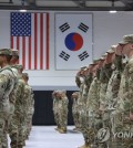 This undated file photo shows troops saluting, with the U.S. and South Korean national flags in the background. (Yonhap)