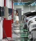 This photo taken Aug. 16, 2023, shows a woman charging her electric vehicle at a charging station in Seoul. (Yonhap)